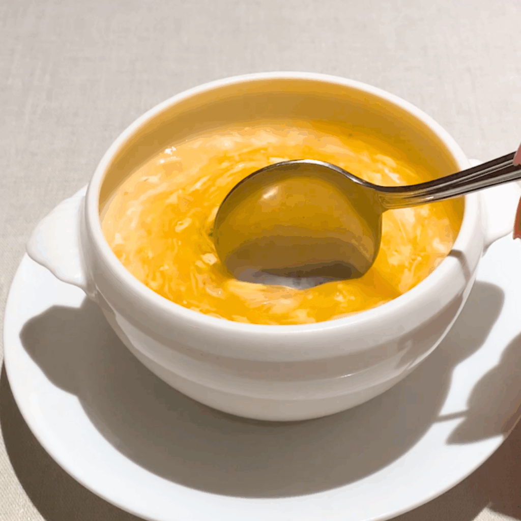 とろみのあるスープにスプーンを差し込む様子。濃厚な質感が強調された写真。