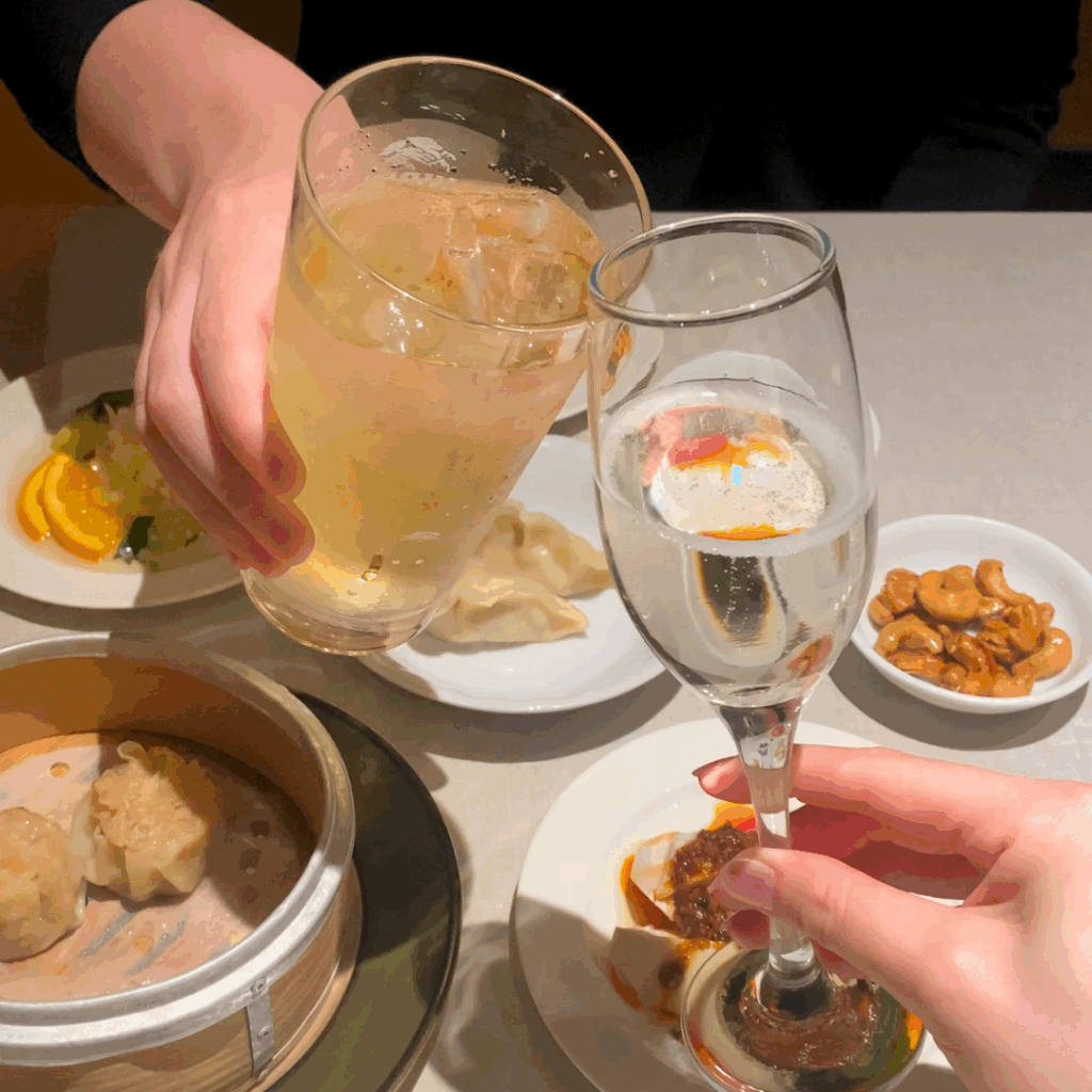 おつまみが並ぶテーブルで、二人がグラスを合わせて乾杯するシーン。ほろ酔い壺中夜の二人飲みの楽しさを表現。