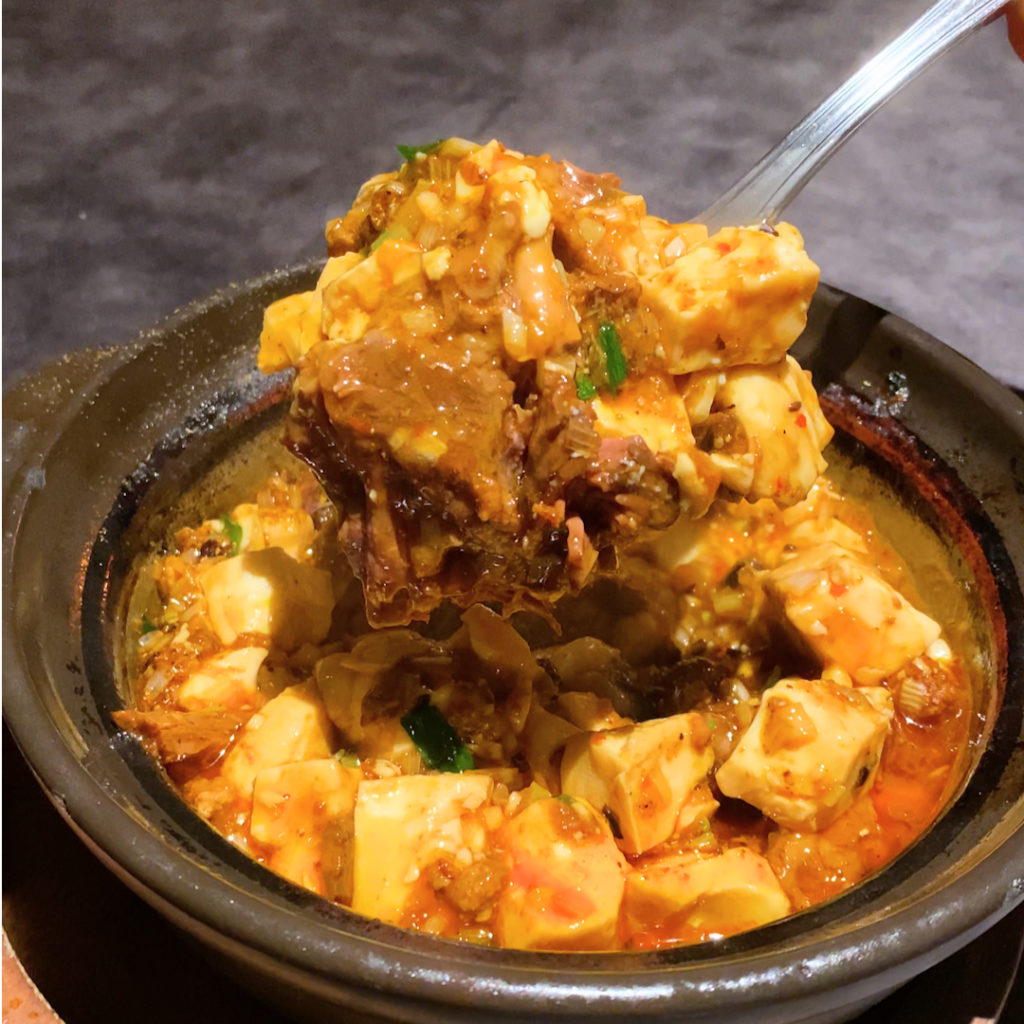 ぼっかけ陳麻婆豆腐をスプーンですくう瞬間。とろりとした豆腐と牛すじが絡む旨辛の食感。
