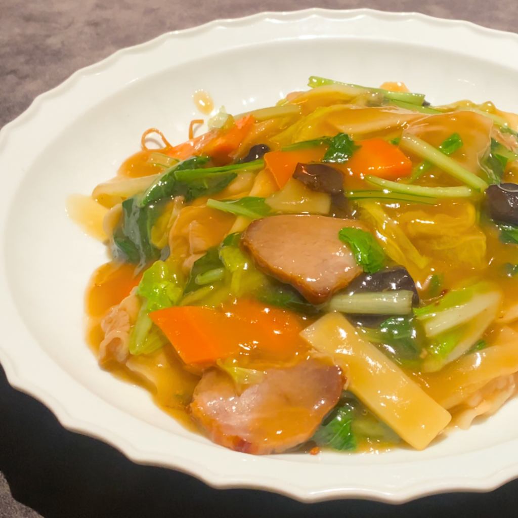 香ばしく焼き上げた麺に、熱々の肉餡がたっぷりかかった焼きそばのアップ写真。濃厚な旨みが広がる一皿。