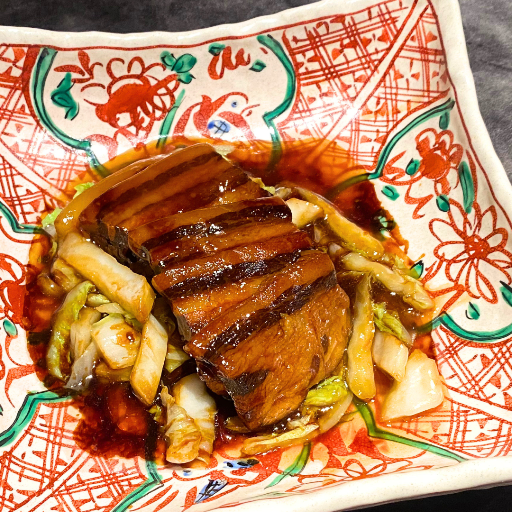 豚バラと天津冬菜の重ね蒸し煮。つややかなタレに包まれた豚バラと漬物が美しく盛り付けられた皿