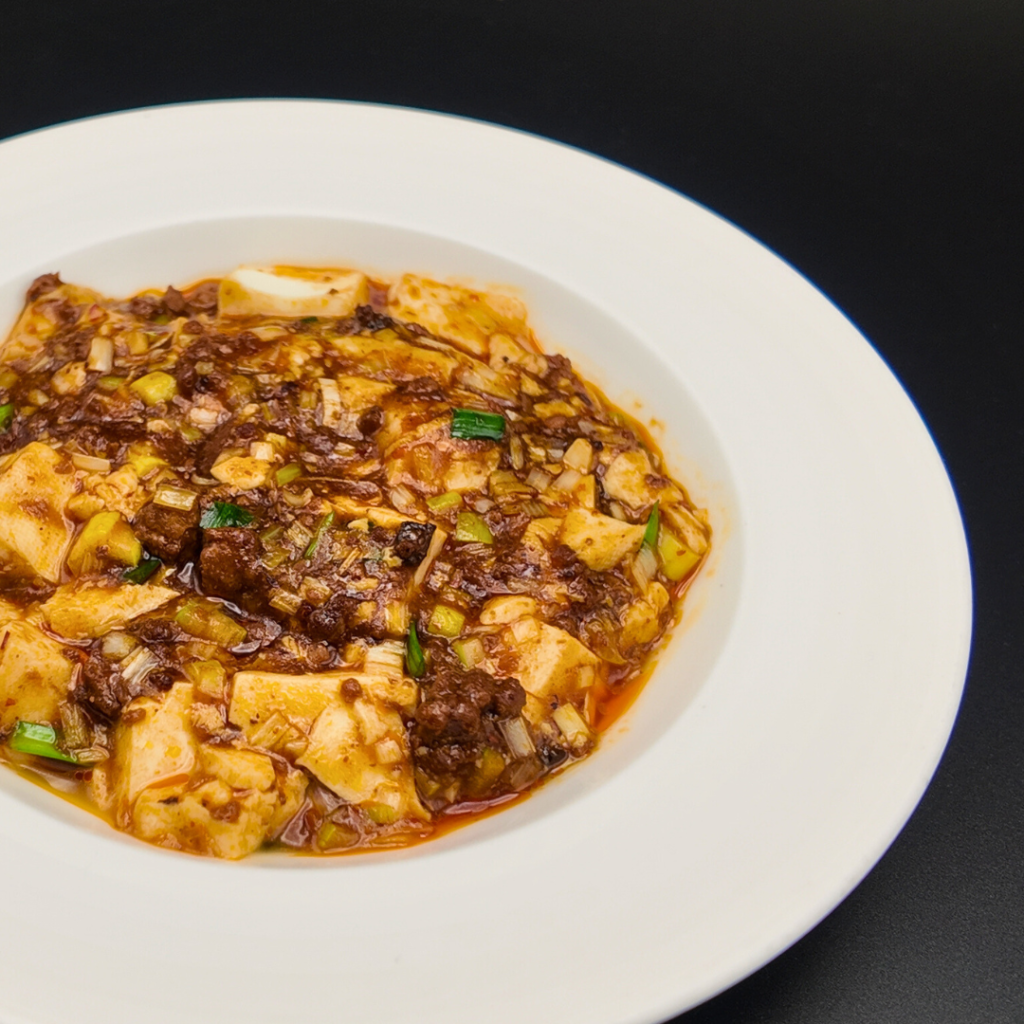 麻婆豆腐。花椒が香るコク深い味わいで、熱々の豆腐と旨味豊かな餡が食欲をそそる。歓送迎会のテーブルを温める定番の一皿。